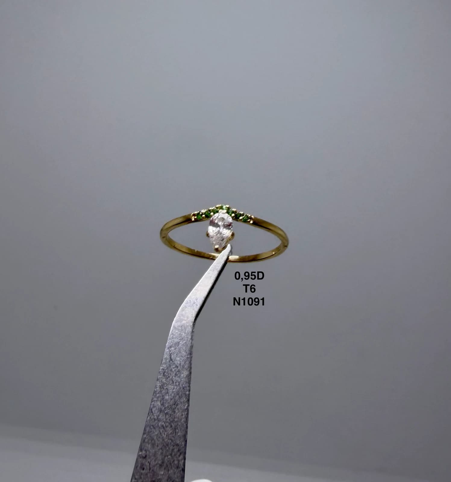 Anillo con piedra clara sostenido con pinzas