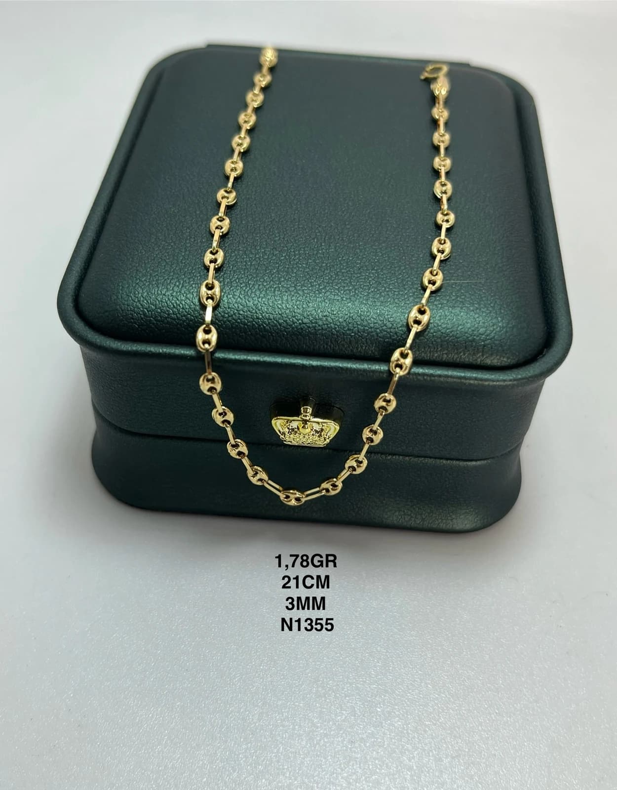 Pulsera de eslabones finos sobre un estuche verde